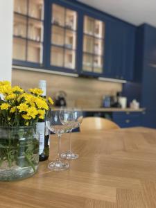 deux verres à vin et un vase avec des fleurs jaunes sur une table dans l'établissement Apartament przy plaży Willa Redłowo, à Gdynia