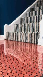 a set of stairs with a red tile floor and a red and grey carpet at Victorian quirky farm cottage next to forest & close to beach in Woodbridge