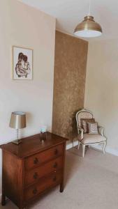 a room with a dresser and a chair and a lamp at Victorian quirky farm cottage next to forest & close to beach in Woodbridge