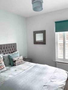 a white bedroom with a large bed and a mirror at Victorian quirky farm cottage next to forest & close to beach in Woodbridge