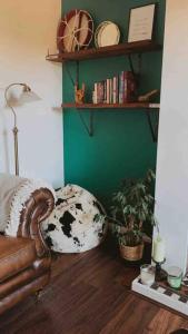 a living room with a couch and a green wall at Victorian quirky farm cottage next to forest & close to beach in Woodbridge