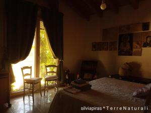 a bedroom with a bed and two chairs and a window at B&B Fiadora Artist House in Decimoputzu