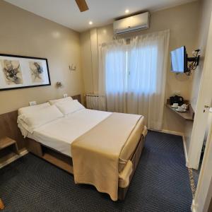 Habitación de hotel con cama grande y TV en Hotel Arcos en Mar del Plata