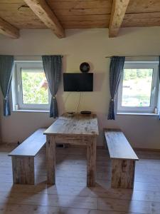 einen Tisch und Bänke in einem Zimmer mit zwei Fenstern in der Unterkunft CasaBleiberg - Garten Apartment - Naturpark Dobratsch in Bad Bleiberg