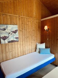 a bed in a wooden room with two paintings on the wall at Løken Camping - trivelig og idyllisk ved vannet in Olden