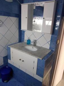 baño azul y blanco con lavabo y espejo en Like my house en Skíathos