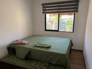 ein kleines Schlafzimmer mit einem grünen Bett und einem Fenster in der Unterkunft Ancla 201 Departamento Familiar in Altata