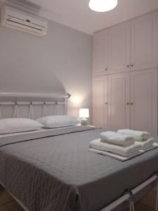 een witte slaapkamer met een bed met handdoeken erop bij Like my house in Skiathos-stad