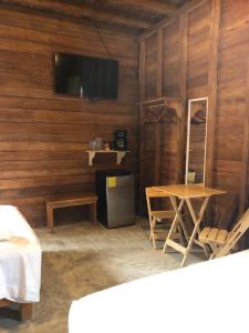 Habitación con pared de madera, mesa y TV. en Cabañas Chac Mool, en Isla Holbox