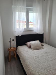 a small bedroom with a bed and a window at Explore the Croatian Coast and Relax in Modern Comfort in Kaštela