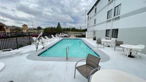 a swimming pool with chairs and a table and a building at Quality Inn Merriam Kansas City in Merriam