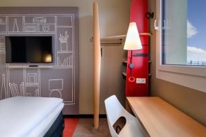 a room with a bed and a desk and a tv at ibis Landshut City in Landshut