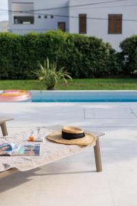 un cappello seduto su un tavolo accanto alla piscina di Villa Botanica - New family house near the sea a Kaštela (Castelli)