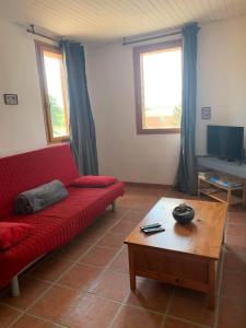 Sala de estar con sofá rojo y mesa de centro en Le grand gîte en Saint-Beauzély