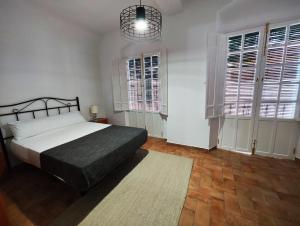 um quarto com uma cama, 2 janelas e um tapete em Casa SANTA MARÍA em Carmona
