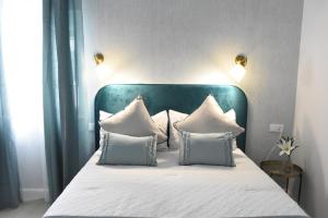a bed with a blue headboard and white pillows at CAPILLITA XXI APARTAMENTOS in Sanlúcar de Barrameda