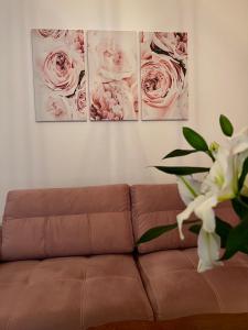 um sofá numa sala de estar com três fotografias na parede em Apartman Krasota em Banja Luka