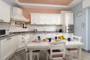 a kitchen with white cabinets and a table with fruits on it at Partenope in Sorrento Coast in Piano di Sorrento