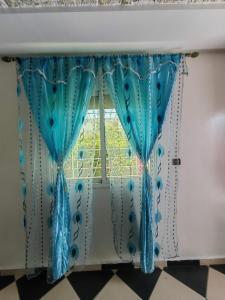 a window with turquoise curtains and beads on it at MOHAMMED AIRPORT LUXURY VILLA in Deroua
