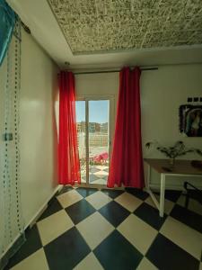 MOHAMMED AIRPORT LUXURY VILLA في Deroua: غرفة مع ستائر حمراء وأرضية مصدية