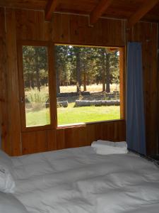 Cama en habitación de madera con ventana en Paralelo 42° Lodge en El Maitén