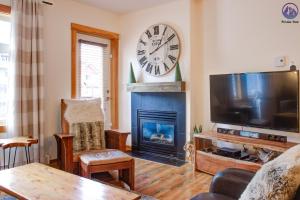 a living room with a fireplace and a large clock on the wall at Modern Nordic 2 Bedroom Mountain View Condo in Canmore