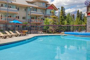 einen Pool in einem Resort mit Stühlen und einem Gebäude in der Unterkunft Modern Nordic 2 Bedroom Mountain View Condo in Canmore