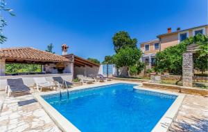 a swimming pool with chairs and a house at Amazing Home In Medulin With Outdoor Swimming Pool in Medulin