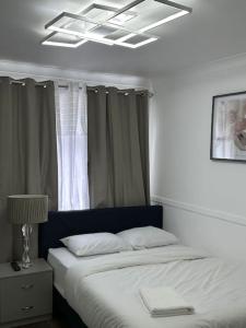 a bedroom with a bed and a window with curtains at Spacious 4 bedroom house in Billericay