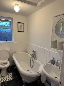 a bathroom with a tub and a toilet and a sink at Spacious 4 bedroom house in Billericay