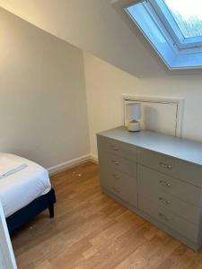 a bedroom with a bed and a dresser with a window at Spacious 4 bedroom house in Billericay