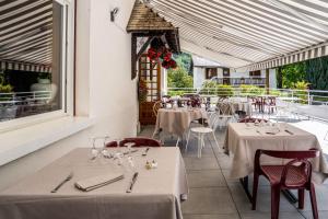 un restaurante con mesas y sillas blancas y una ventana en Logis Le Vieux Logis, en Lestelle-Bétharram