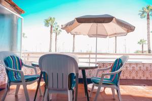 a table with chairs and an umbrella on a balcony at Gran apartamento en primera línea Motril in Motril