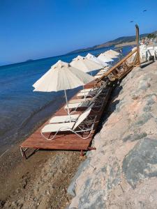 una fila de tumbonas con sombrillas en una playa en Apelles Butik Otel, en Seferihisar