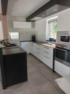 a kitchen with white cabinets and a black counter top at Gite Comme chez soi in Spa