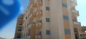 a building with blue windows on the side of it at عمارة الحج موسي بشاطئ أم الرخم عجيبه in Zâwyet Umm el Rakham