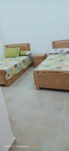two beds sitting in a room with a tiled floor at عمارة الحج موسي بشاطئ أم الرخم عجيبه in Zâwyet Umm el Rakham
