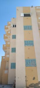 a tall building with windows on the side of it at عمارة الحج موسي بشاطئ أم الرخم عجيبه in Zâwyet Umm el Rakham