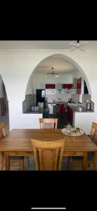 eine Küche und ein Esszimmer mit einem Holztisch und Stühlen in der Unterkunft Appartement Dikki Plage in Melîyech