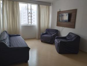 ein Wohnzimmer mit 2 Stühlen und einem Sofa in der Unterkunft Apto 2Q com Escritório Batel in Curitiba