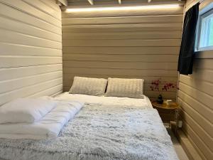 una camera da letto con letto, lenzuola e cuscini bianchi di Lake Cottage with sauna (near City) a Jyväskylä