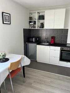 a kitchen with white cabinets and a table and a sink at Apartment Nr. 5 am Stuttgarter Flughafen/Messe in Leinfelden-Echterdingen