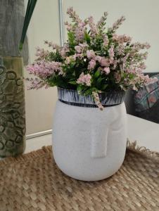 eine weiße Vase mit rosa Blumen auf dem Tisch in der Unterkunft Apartman (stan na dan) M&M Prijedor in Prijedor