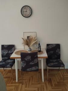 a dining room table with two chairs and a clock on the wall at Apartman (stan na dan) M&M Prijedor in Prijedor