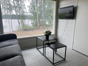 un soggiorno con divano, 2 tavoli e una finestra di Lake Cottage with sauna (near City) a Jyväskylä