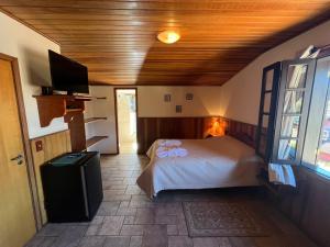 a bedroom with a bed and a flat screen tv at Banyvas Chalés in Monte Verde