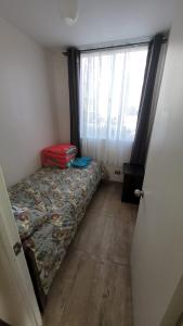 Habitación pequeña con cama y ventana en Departamento a pasos del borde costero en condominio privado, en La Serena