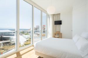 a bedroom with a white bed and a large window at Porto Real Hotel in Finisterre