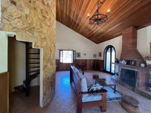 a living room with a fireplace and a stone wall at Banyvas Chalés in Monte Verde
