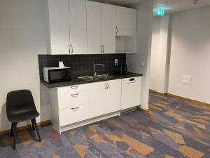 a kitchen with white cabinets and a sink and a chair at Ahlgrens Hotell Bed & Breakfast in Gävle